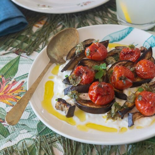 Piatto di Melanzane e pomodorini arrostiti con stracciatella sulla tavola