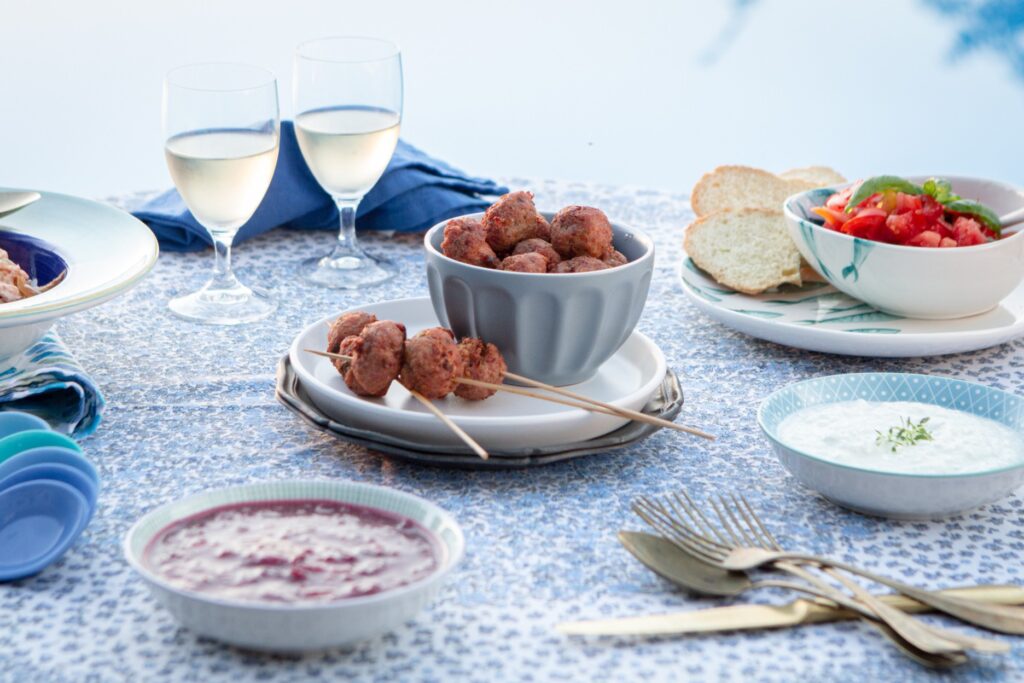Tavola apparecchiata con piatto di polpette e bicchieri di vino bianco